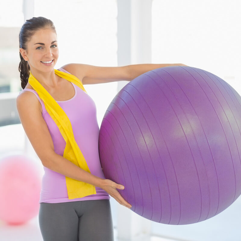 Junge Frau hält lila Gymnastikball